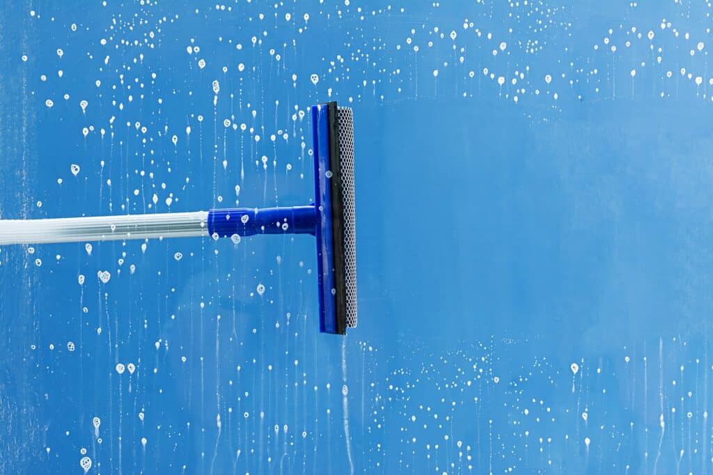 Rubber squeegee cleans window. Clears a stripe of soaped window. Cleaning service concept.